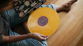 Un disc galben fiind scos din husa sa de un bărbat așezat pe podea