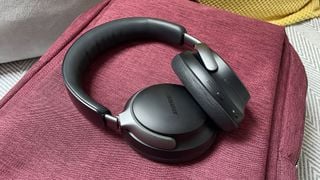 Căști Bose QuietComfort Ultra negre pe o geantă roșie.