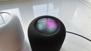 Un Apple HomePod 2 negru pe o suprafață albă cu panoul superior vizibil.