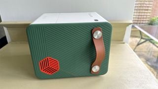 Proiector home cinema BenQ GS50, din lateral pe suprafață de lemn, arătând mânerul de transport