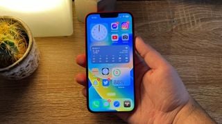Apple iPhone 14 în mână lângă o lampă