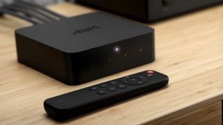 Unitate WiiM Pro Plus cu telecomandă neagră mică în față, ambele plasate pe un raft de lemn