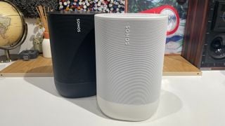 Un Sonos Move negru așezat ușor în spatele unui Move 2 alb