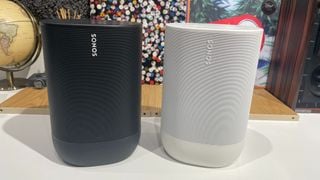 Un Sonos Move negru și un Sonos Move 2 alb unul lângă altul pe un birou