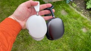 O mână care ține Sonos Ace în alb și Apple AirPods Max în negru
