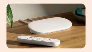O imagine scăpată cu un streamer Google TV alb și o telecomandă pe o suprafață de lemn.