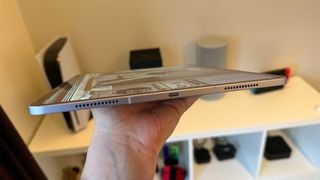 iPad Air de 13 inchi ținut plat într-o mână, arătând marginea de jos.