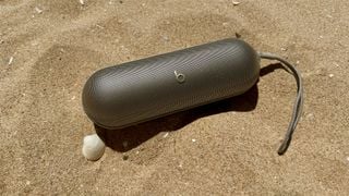 Boxă Bluetooth Beats Pill pe plajă nisipoasă lângă o scoică