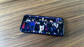 Apple iPhone 15 Pro Max pe o masă de lemn cu Ted Lasso pe ecran