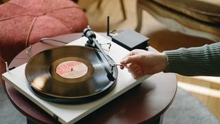 Pick-up Pro-Ject Primary E1 cu o mână punând acul pe un disc de vinil