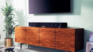 Sennheiser Ambeo Soundbar Max on a side table sat underneath a wall-mounted television