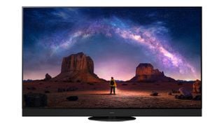 Televizor OLED Panasonic Z95A pe un fundal alb. Pe ecran este o persoană într-un deșert privind către o constelație de stele.