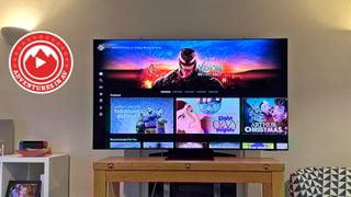 Un televizor Samsung de 65 de inch pe un suport din lemn într-o sufragerie. Pe ecran este pagina principală a Sony Pictures Core de pe PS5, cu un banner mare pentru filmul Venom: The Last Dance.
