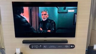 Televizor LG G5 montat pe un perete din lemn cu un soundbar dedesubt