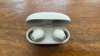 Căști Sony WF-1000XM5 în carcasă pe suprafață de birou din lemn