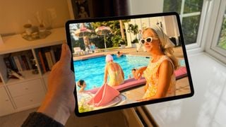 iPad Air de 13 inchi ținut într-o mână. Pe ecran este o imagine din Palm Royale.