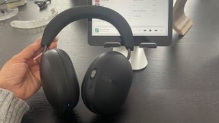 Căști wireless Sonos Ace ținute în fața unui iPad