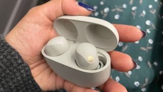 Căști și carcasă Sony WF-1000XM5 ținute în mână