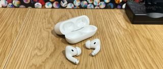 Apple AirPods Pro de prima generație cu carcasa lor de încărcare pe o masă de lemn