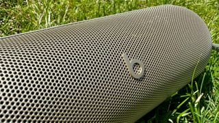 Boxă Bluetooth Beats Pill pe iarbă, detaliu pe grilă și logo Beats