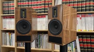Kerr Acoustic K300 Mk3 pe suporturi în fața unei biblioteci