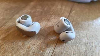 Bose Ultra Open Earbuds pe o masă de lemn