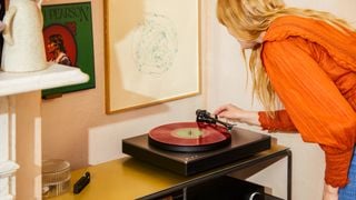 Pick-up Cambridge Audio Alva ST într-un decor de lifestyle cu o femeie punând acul pe vinil