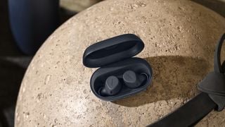 Căști Jabra Elite 7 Active negre în cutia de încărcare pe o bilă de piatră.