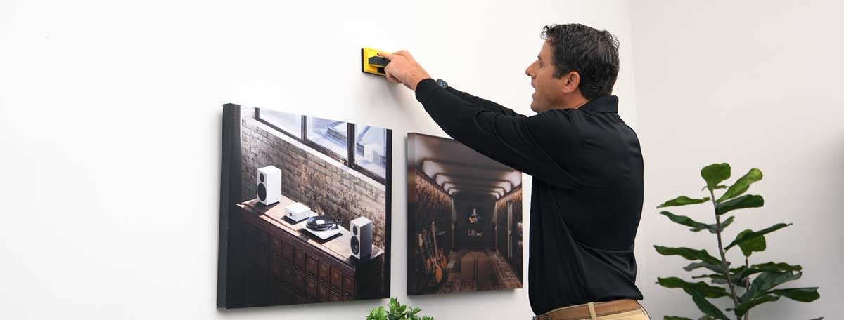 Bărbat verificând peretele de obstacole cu un detector de montanți