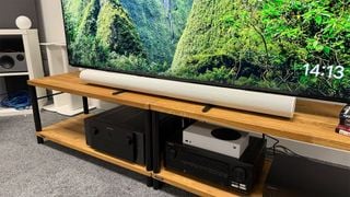 Soundbar Sonos Arc Ultra pe rack AV sub televizor cu scenă din natură pe ecran