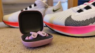 Beats Fit Pro în fața unei perechi de adidași
