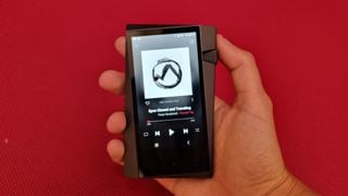 Astell & Kern A&norma SR35 în mână pe un fundal roșu