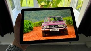 Tableta Amazon Fire HD 10 (2023) ținută în mână în fața unei ferestre cu mașină pe ecran