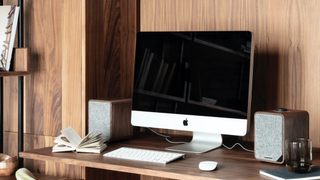Boxe Ruark MR1 Mk2 lângă un ecran desktop Apple Mac într-un birou de acasă cu fundal de lemn