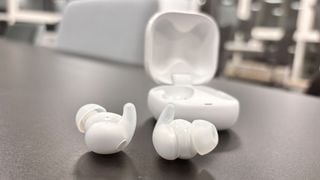 Căștile intraauriculare Sony LinkBuds Fit pe suprafață gri lângă carcasa deschisă