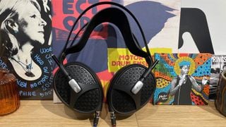 Căști deschise Meze Audio Empyrean II sprijinite vertical pe un raft de lemn