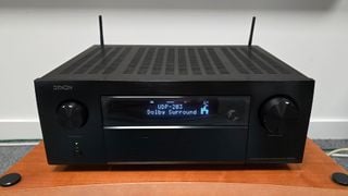 Denon AVC-X6800H unghi de sus pe față al amplificatorului AV pe un raft din lemn