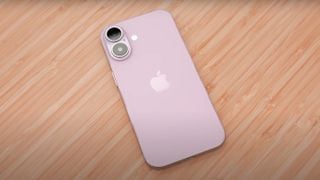 Un model dummy roz de iPhone 16 așezat pe o suprafață de lemn, afișând sigla Apple pe spate.