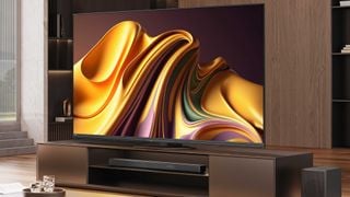 Televizorul Hisense U8N pe un suport media din lemn în fața unei unități de rafturi din lemn. Pe ecran este o grafică unduitoare în principal aurie, cu elemente violet și verde.