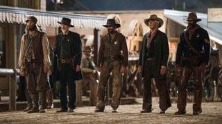 Cinci personaje de tip cowboy stând într-o linie