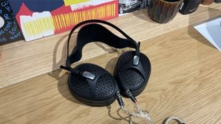 Căști deschise Meze Audio Empyrean II așezate orizontal pe o masă de lemn
