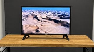 Televizor RCA Roku de 24 de inchi (RK24HF1) pe suport de lemn, cu dune de nisip pe ecran