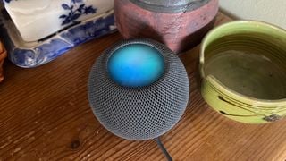 HomePod Mini cu panoul superior luminând albastru când Siri este activat