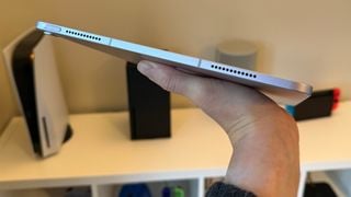 iPad Air de 13 inchi ținut plat într-o mână, arătând marginea de jos.