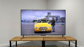 Amazon Fire TV Omni QLED pe un suport din lemn cu o imagine din The Grand Tour pe ecran