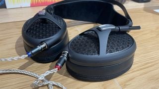 Căști deschise Meze Audio Empyrean II așezate orizontal, arătând conexiunile de cablu