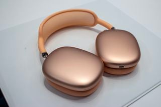 AirPods Max 2 portocalii pe un blat de lucru gri