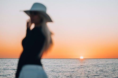 a woman in a hat and a sunset