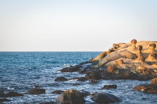 a rocky shore with water and a person standing on it