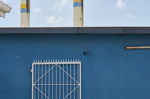 a blue wall with a gate and smoke stacks